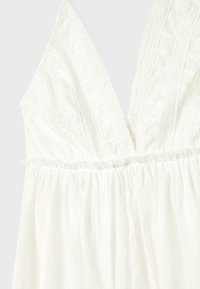 Weißes ärmelloses Kleid mit tiefem V-Ausschnitt, Spitzenverzierungen und geraffter Taille. Verfügt über einen strukturierten Stoff und ein fließendes Design.