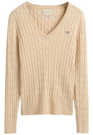 Pull beige à col en V en maille torsadée, manches longues, poignets et ourlet côtelés, avec un petit logo brodé sur la poitrine.