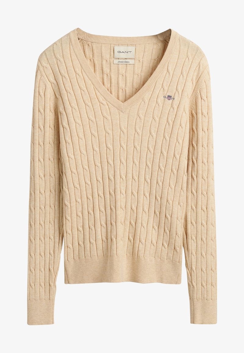 Pull beige à col en V en maille torsadée, manches longues, poignets et ourlet côtelés, avec un petit logo brodé sur la poitrine.