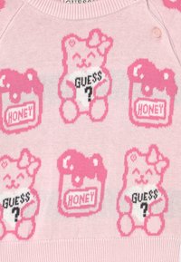 Sweater rosa de malha com padrões repetidos de ursos e frascos de mel, com texto preto a dizer "GUESS?" e "HONEY."