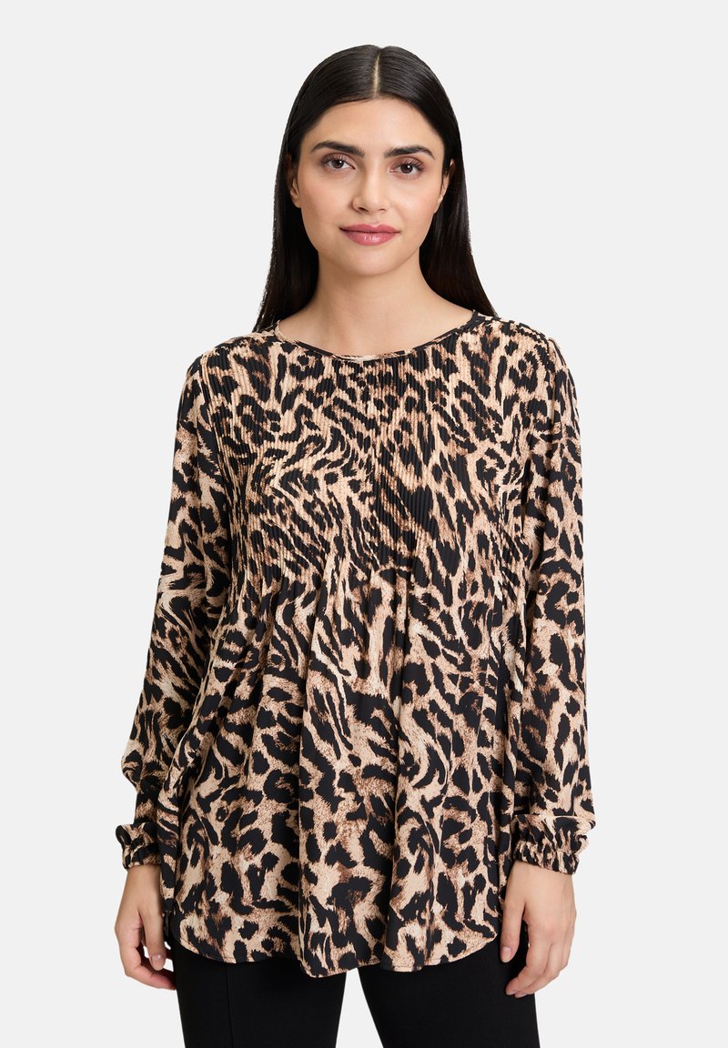Blouse à imprimé léopard en beige et noir, avec des manches longues, des détails plissés et des poignets élastiques. Tissu léger avec une coupe décontractée.