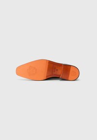 Semelle de chaussure en cuir marron avec une finition lisse, présentant un dessous orange et un détail de logo en relief. La forme est incurvée avec un bout pointu.