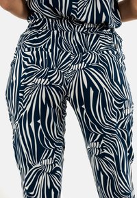 Pantaloni navy con motivo a foglia astratto bianco, vita elastica e tasche laterali, realizzati in un tessuto leggero e testurizzato.