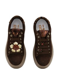 Sneaker in suede marrone con un accento floreale sulla scarpa sinistra, occhielli dorati e suole in gomma marrone chiaro. Tessuto testurizzato e dettagli di design.