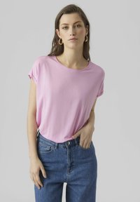 Pink short-sleeve tee made of soft fabric, with a round neckline and relaxed fit, paired with high-waisted blue jeans.