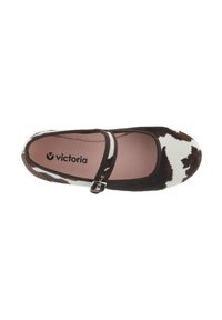 Zapato de ballet con estampado de vaca marrón y blanco, con correa al tobillo; material suave y diseño de punta redonda; el interior presenta el nombre de la marca en negro.