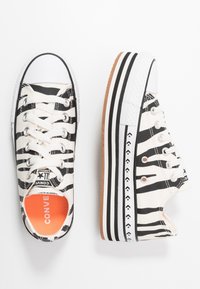 Baskets en toile à imprimé zèbre avec rayures noires et blanches, embout en caoutchouc et semelle en caoutchouc beige agrémentée d'accents texturés blancs et noirs.