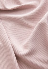 Miękki, jasnoróżowy prążkowany materiał o gładkiej fakturze, z delikatnymi pionowymi liniami i subtelnymi fałdami.