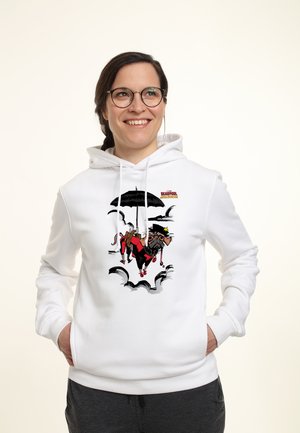 Uśmiechnięta kobieta w okularach nosi białą bluzę z kapturem z nadrukiem kreskówkowego psa ucharakteryzowanego na Deadpoola, trzymającego parasol, unoszącego się wśród chmur.
