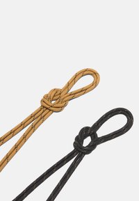 Dos cuerdas en oro y negro, cada una con texturas tejidas y nudos, presentando patrones y lazos sutilmente contrastantes en los extremos.