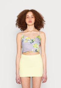 Top de lavanda cortado com padrão floral, alças finas e frente franzida; combinado com uma mini saia amarela clara texturizada.