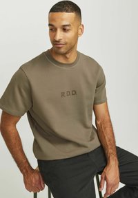 Olivově zelené tričko s krátkým rukávem a kulatým výstřihem, na přední straně s jemným potiskem "R.D.D.". Hladká textura, materiál s podílem bavlny.