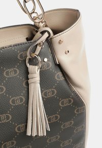 Bolso texturizado con cuerpo en verde oscuro con un patrón de logotipos y acentos en beige claro, herrajes dorados y un detalle de borla.