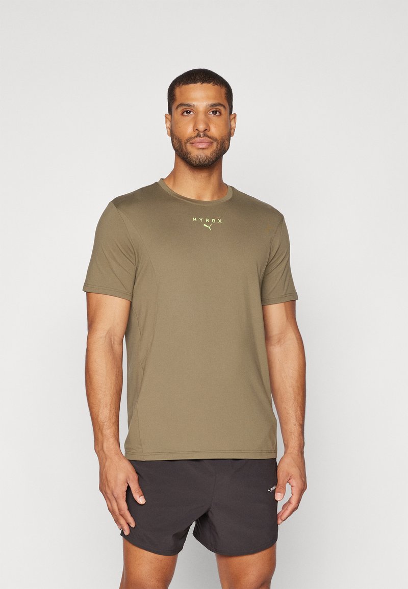 T-shirt atlético de mangas curtas em verde-oliva com decote redondo e logo HYROX em amarelo. Feito de um tecido leve e que absorve a humidade.