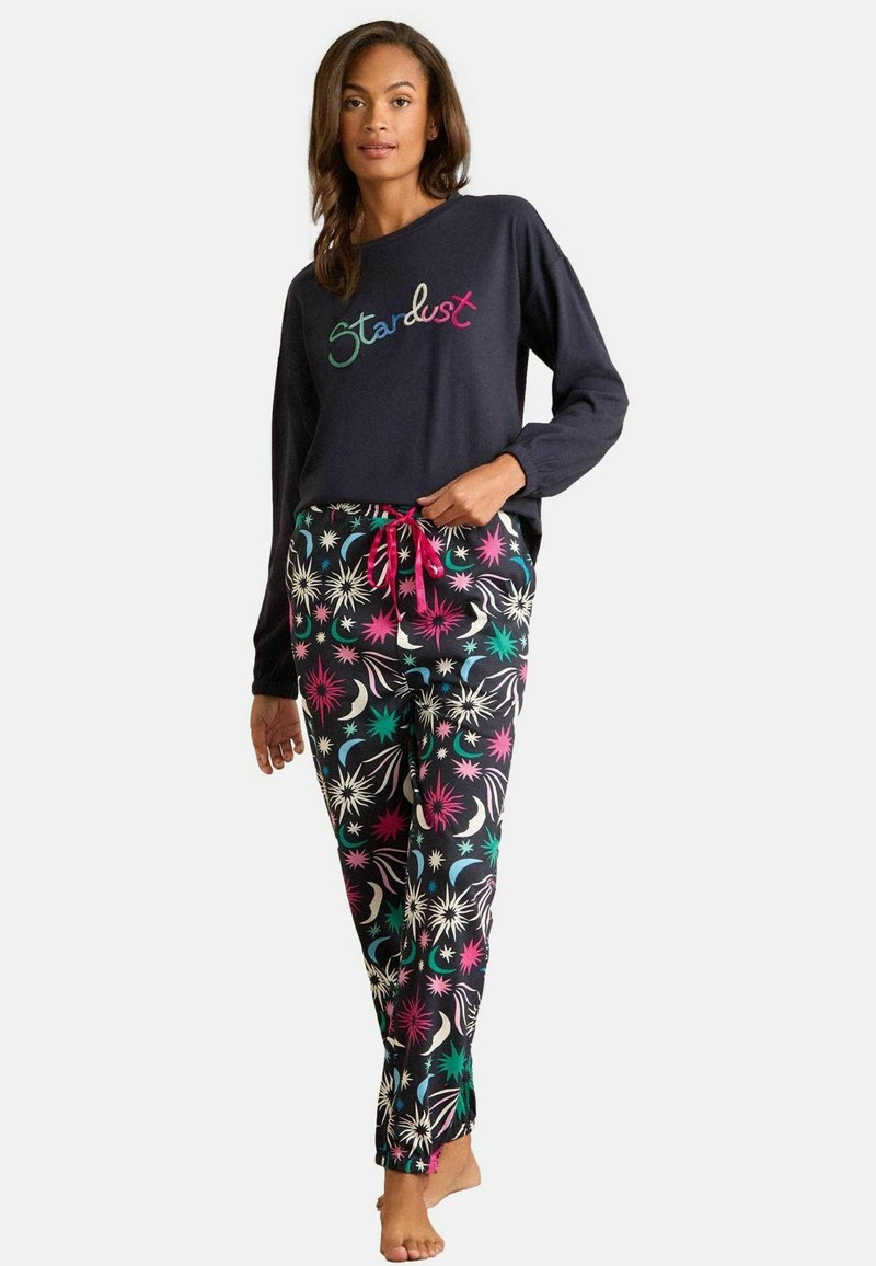 Marine sweatshirt met de tekst "Stardust", gecombineerd met multi-kleurige, gemusterde pyjamabroek met bloemen- en sterrenmotieven, accentueert met een roze trekkoord.