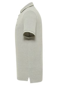 Polo shirt gris clair en tissu texturé. Il présente un col classique, des manches courtes, une patte de boutonnage et des fentes sur les côtés à l'ourlet.