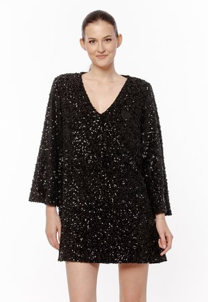 Czarna sukienka z cekinami, z dekoltem w kształcie litery V i rękawami trzy czwarte. Luźny, teksturowany materiał z zabawną, błyszczącą powierzchnią.