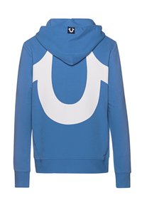 Sweat à capuche bleu avec une grande forme de fer à cheval blanche dans le dos et une petite étiquette noire au centre supérieur de la capuche.