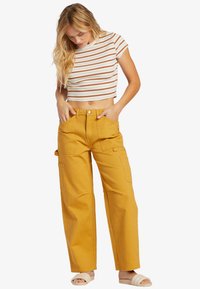 Gula cargobyxor med avslappnad passform, som har stora fickor och en mjuk bomullstextur, i kombination med en figurnära, randig crop top.