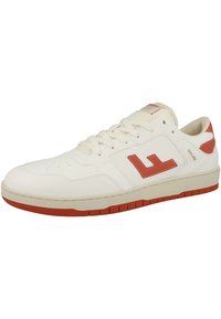White leather sneaker with red accents, flat sole, perforated toe box, round laces, and branding on the side and tongue.