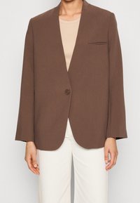 Blazer marrón con cierre de un solo botón, solapas con muesca, diseño ligeramente sobredimensionado y un bolsillo en el pecho. Textura suave, tela ligera.