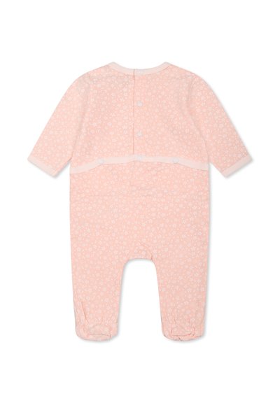 Grenouillère rose pâle avec petit motif floral blanc, manches longues, et boutons-pression dans le dos et entre les jambes. Tissu doux.