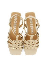 Sandalias de plataforma beige con múltiples capas de tiras adornadas con pequeños clavos metálicos. Cierre de hebilla y diseño de punta cuadrada.