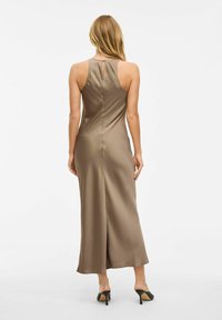 Smeđa satenasta maksi haljina s detaljem proreza na leđima, koja ima uski korzet i suknju koja se širi. Tkanina izgleda glatko i elegantno.