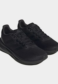 Czarne buty sportowe wykonane z siateczkowego materiału z fakturowanymi akcentami, płaskimi sznurówkami i wyściełaną podeszwą, charakteryzujące się smukłym wzornictwem.