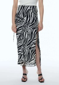 De afbeelding toont een lange, doorschijnende rok met een zwart-wit zebrapatroon, een split aan de zijkant en een getailleerde taille.