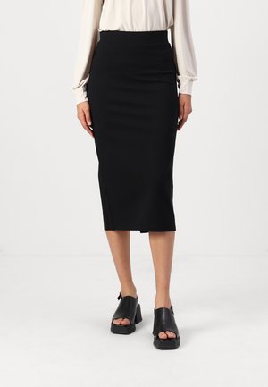 Svart midi blyantskjørt med en tettsittende design, glatt tekstur og høy midje. Fått sammen med svarte åpen tå blokkhæler.