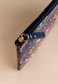 Navy torbica z rožnatim vzorcem, ki vključuje gladko teksturo, zlat pribor in raven dizajn z živahnimi barvami in akcenti.