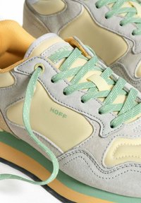 Zapatillas de ante gris con suaves acentos amarillos y verdes, que cuentan con superposiciones texturizadas, cordones planos y una suela de goma multicolor.