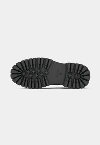 Black rubber outsole with deep treads, featuring cross patterns for traction and a smooth central area. Stamped branding visible.