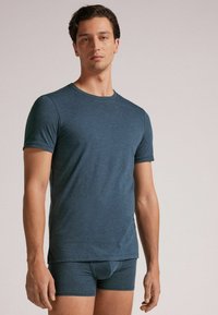 Tmavě modré tričko s krátkým rukávem vyrobené z měkké, elastické tkaniny, doplněné o odpovídající obepnuté šortky. Hladká textura a jednoduchý design.