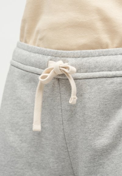 Οι γκρι φόρμες έχουν απαλή υφή και ελαστική μέση με μπεζ κορδόνι. Το ύφασμα φαίνεται άνετο και καθημερινό.