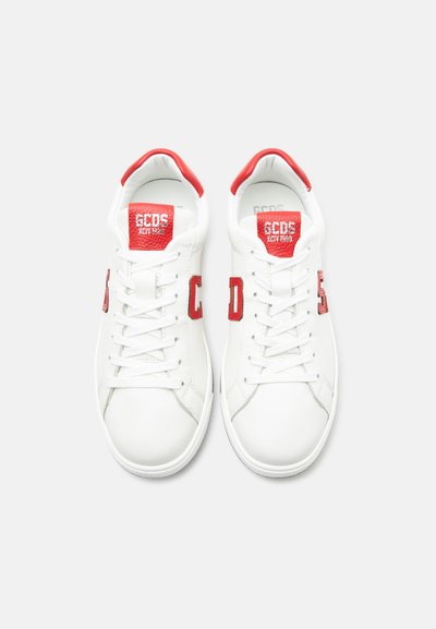 Ζευγάρι λευκά sneakers με κόκκινες λεπτομέρειες, γράμματα "GCDS" στη γλώσσες και στις πλευρές, λευκά κορδόνια και κόκκινοι λαιμοί στη φτέρνα, σε θέα από πάνω.