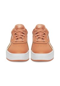 Pár béžových sneakers Reebok s bielymi podrážkami, pohľad z prednej strany, zobrazuje šnúrky a perforovanú špičku na bielom pozadí.