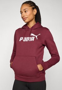 Bordo dukserica s kapuljačom koja ima kengurudu, rebraste manšete i veliki bijeli logo "PUNIA" sa siluetom Pume na prsima.