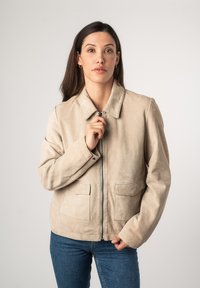 Beige Wildlederjacke mit Kragen, Frontreißverschluss und zwei aufgesetzten Taschen. Bietet eine lässige Passform und eine glatte Textur.