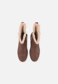 Brown suede ankle boots with a soft cream faux fur lining, rounded toe, and side pull tab, featuring a stitched seam detail.