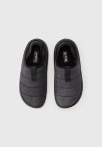 A fekete slip-on Crocs papucsok párja, steppelt felsőrésszel és húzófülekkel, felülről nézve fehér háttéren.