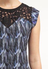 Encolure en dentelle noire avec un tissu à motif de feuilles dans des nuances de bleu et de gris, manches courtes, texture douce, design ajusté.