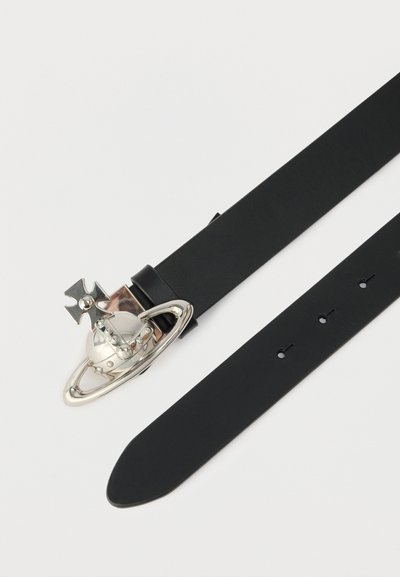 Μαύρη δερμάτινη ζώνη με γυαλιστερή ασημένια αγκράφα σε σχήμα πλανήτη με δαχτυλίδια και σταυρό στην κορυφή, τοποθετημένη επίπεδη σε λευκή επιφάνεια.