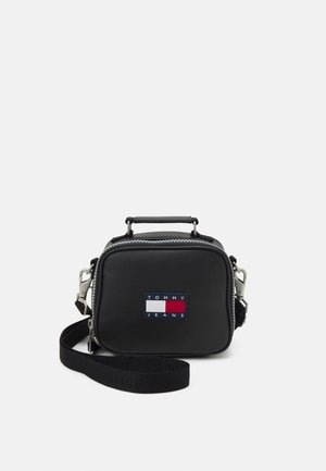Pequeño bolso bandolera rectangular negro con asa superior, cierre de cremallera, correa ajustable y parche con el logo de Tommy Jeans en el frente.