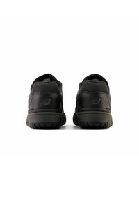 Chaussures de sport noires avec une tige texturée, un col rembourré et des semelles en caoutchouc. Présente un logo en relief et un design élégant et minimal.