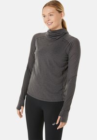 Haut de sport à manches longues en tissu gris foncé avec un col drapé, des trous pour les pouces dans les manches et des détails de ventilation découpés au laser.