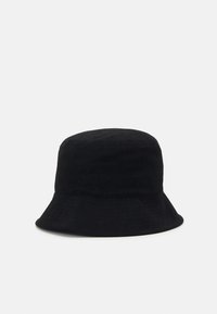 Cappello a secchiello nero realizzato in materiale corduroy, con una superficie testurizzata e una visiera ampia che declina verso il basso.