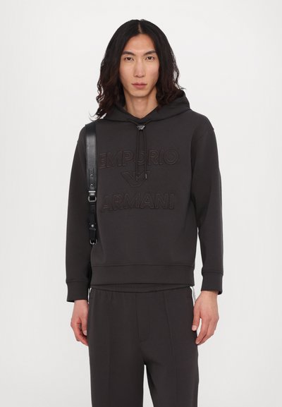 Hoodie cinza escuro feito de um tecido macio, apresentando um logo bordado em destaque, cordão ajustável e punhos canelados. Combinado com calças a condizer.