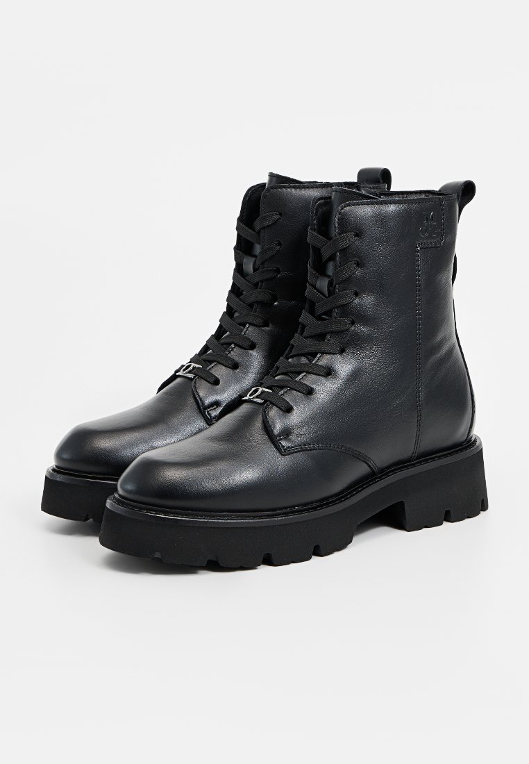 Zwarte leren veterschoenen met een ronde neus, dikke rubberen zool en een gestructureerde afwerking. Voorzien van metalen oogjes en een lus aan de achterkant voor gemakkelijk aan- en uittrekken.